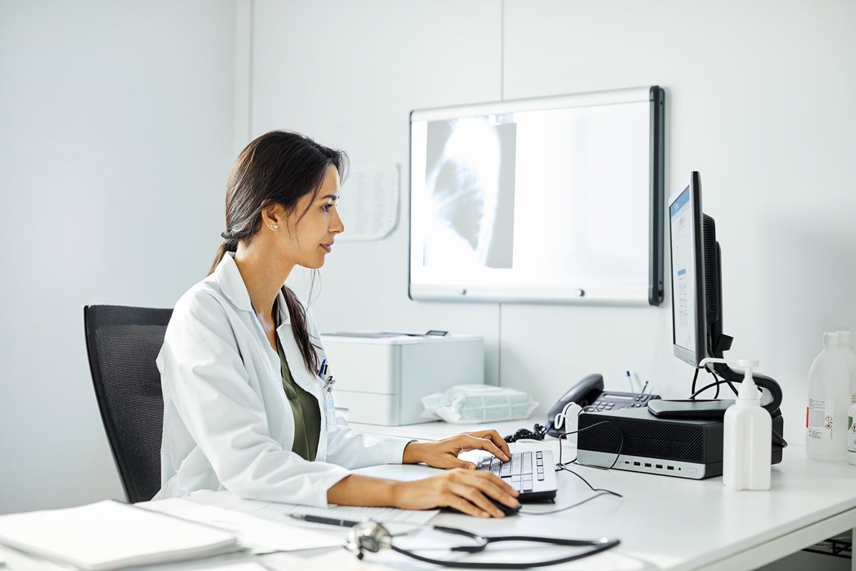 Photo illustration of an employee using a laptop with a holographic display to check figures and graphs.