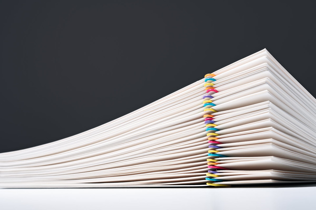 A stack of paper neatly organized with colorful paper clips.