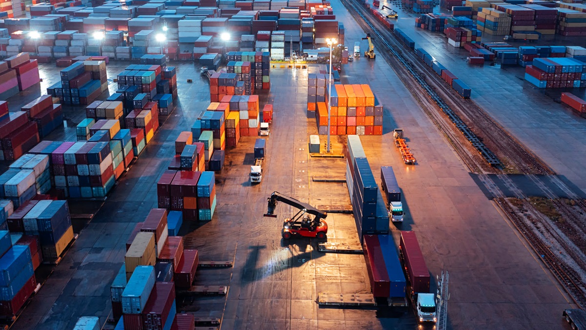 A forklift moves through a packed container warehouse, preparing to load a large container to ready for shipment.