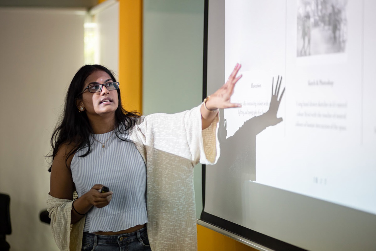 A woman giving a presentation in front of a projector screen.