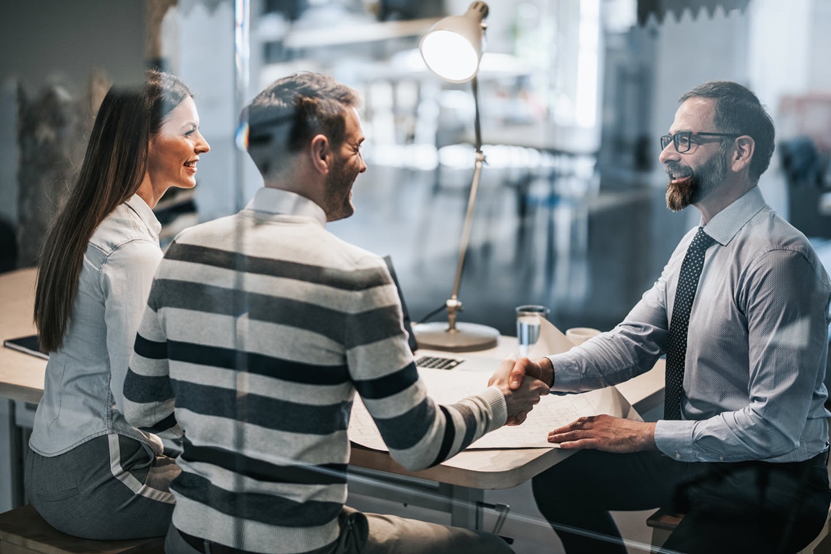 A businessman and client shaking hands over a table.