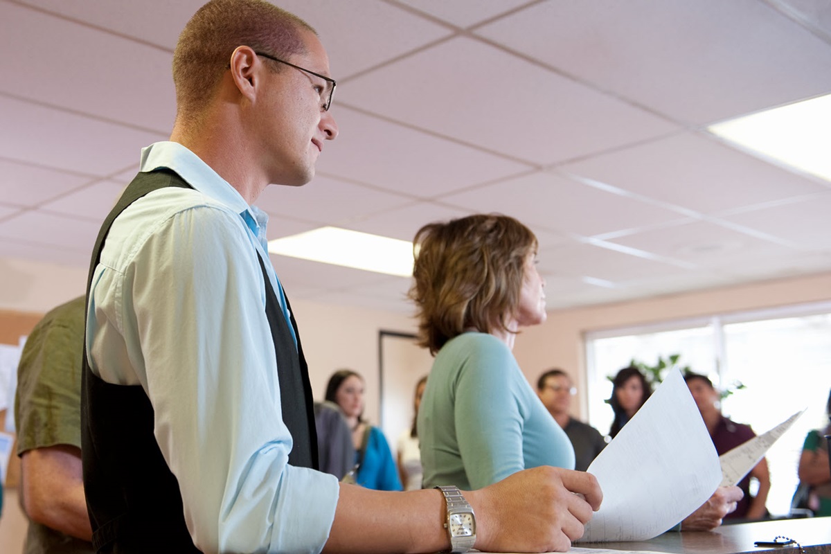 People waiting their turn at the counter of a government office, holding forms printed out with a government printer.