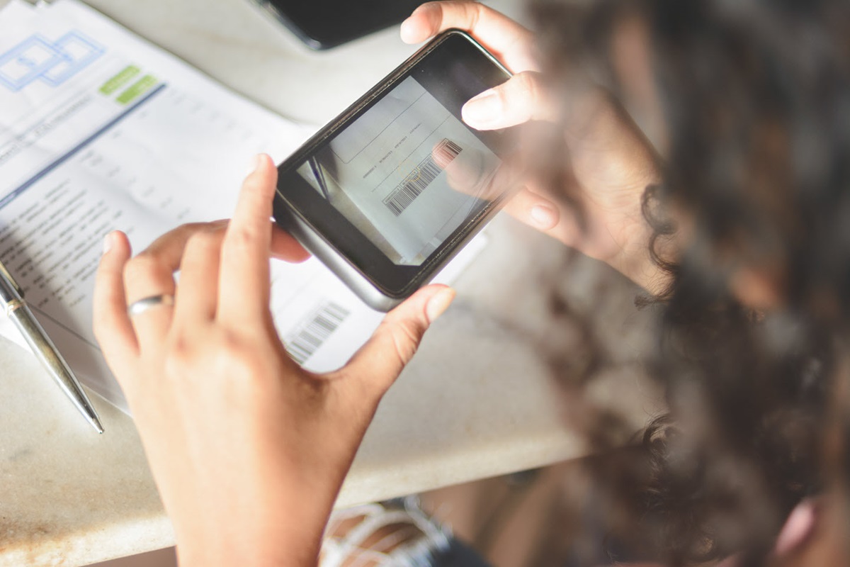 A woman uses her phone camera to scan a document.