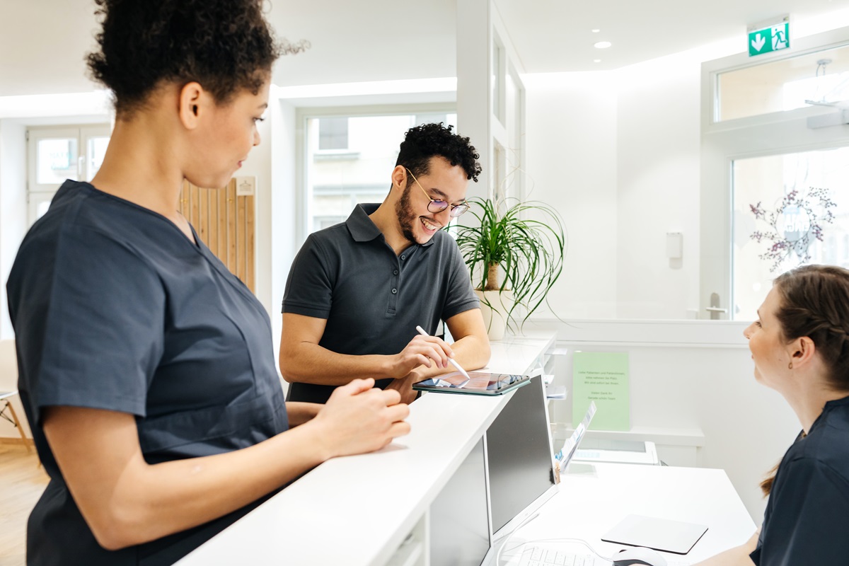Three healthcare office workers at a workstation. 