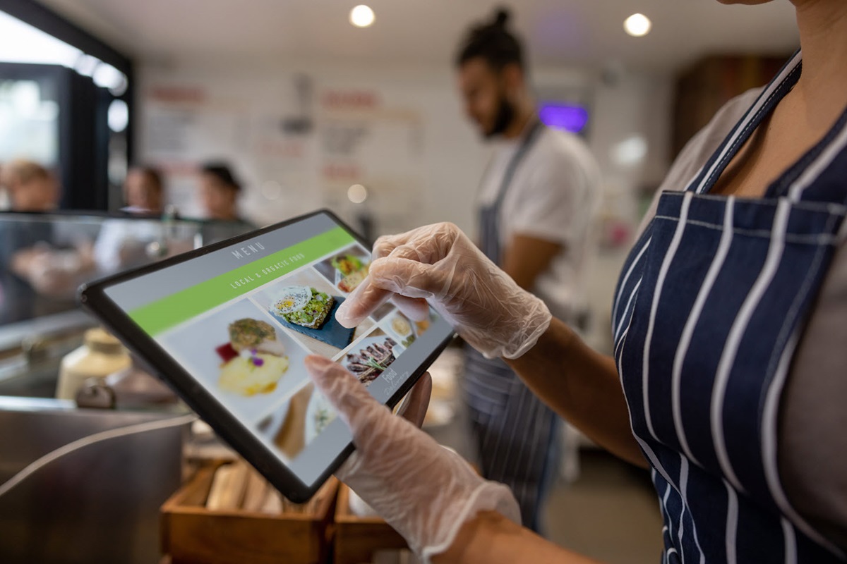 A food service worker makes a selection on a tablet, showing one industry's digital transformation example.