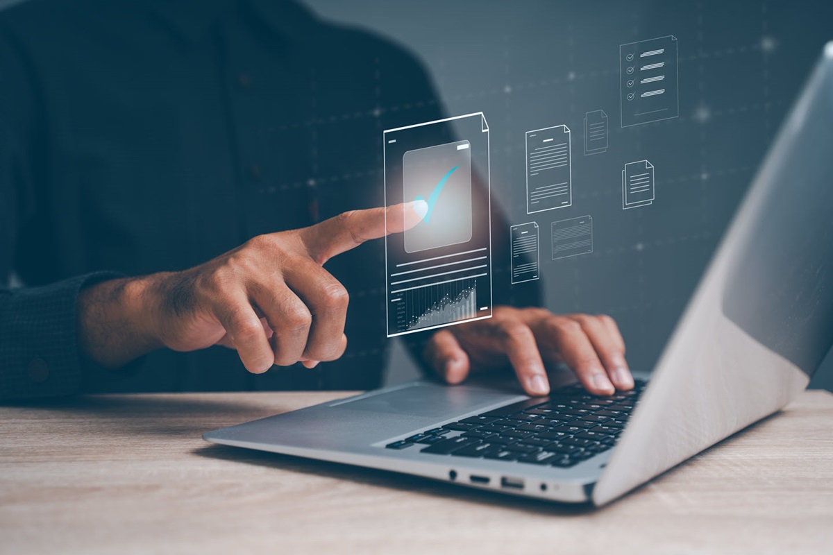 A pair of hands using a laptop. Icons representing digital files appear above the laptop.