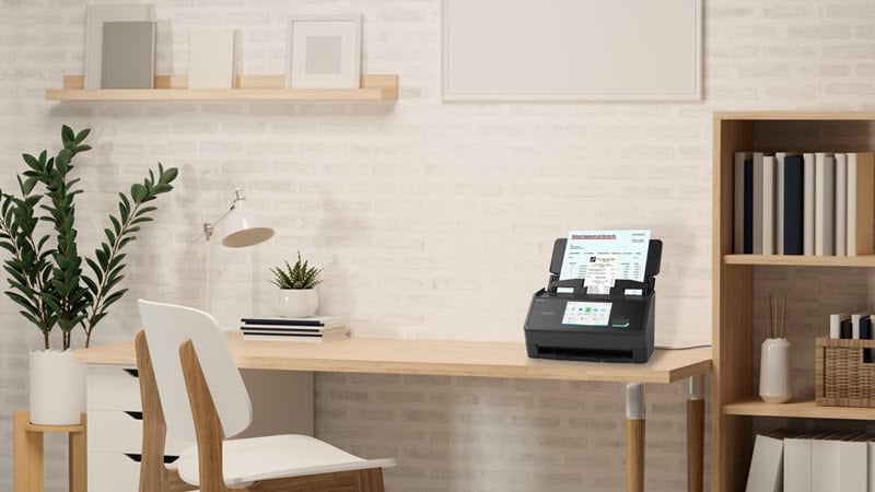 iX2500 scanner in black sitting atop a desk in a clean home. 