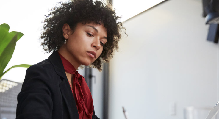 Black woman looking down writing.