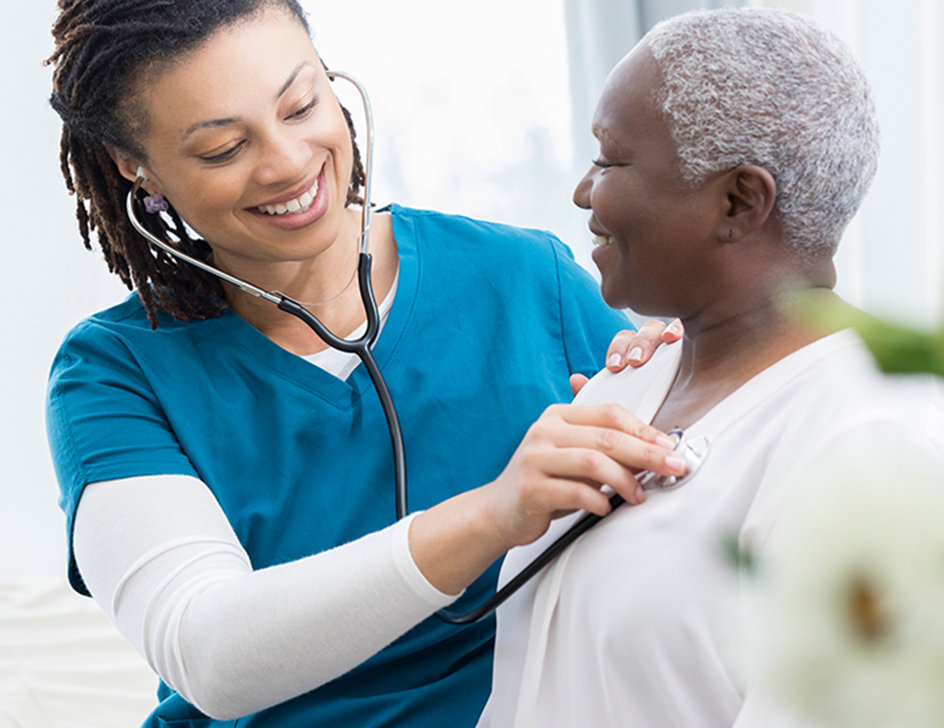 Woman doctor listening to the heartbeat of an older woman.