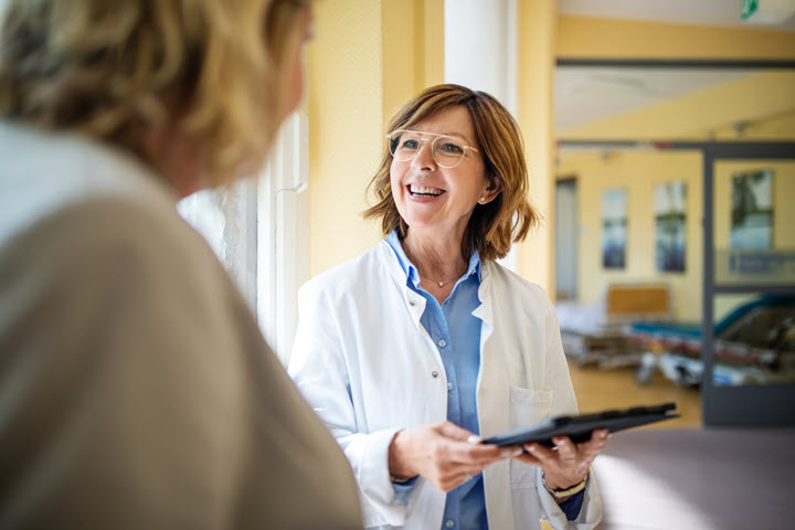 Female doctor smiling at patient that is seated.