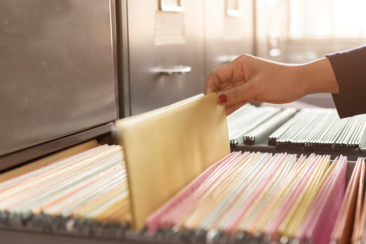 Female hand getting a file from a filing cabinet. 