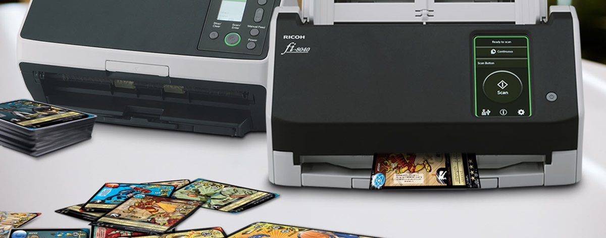 Two Ricoh scanners with trading cards laying near them and inside of them. 