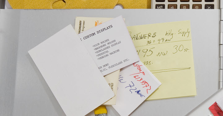 Pile of business cards and notes on a desk. 