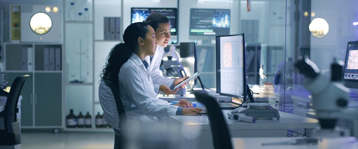 A pair of researchers examines a computer screen in a lab environment.