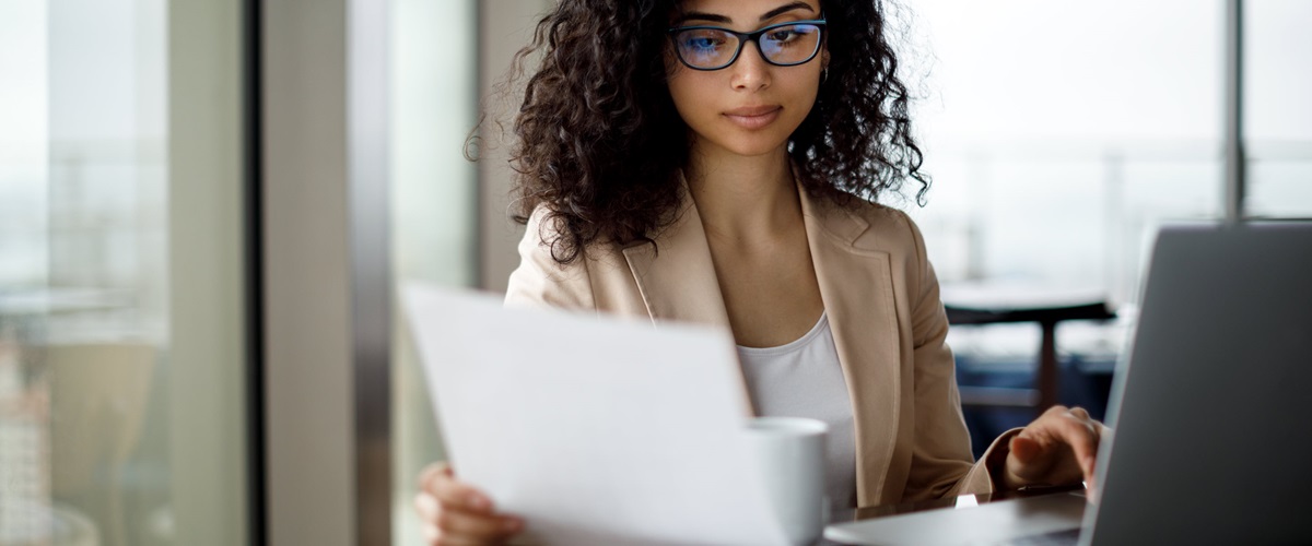 An employee looks over printed documents while seated at a desk.