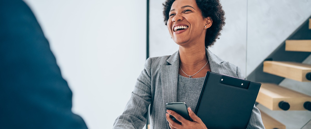 A smiling businesswoman is shaking hands in an office.