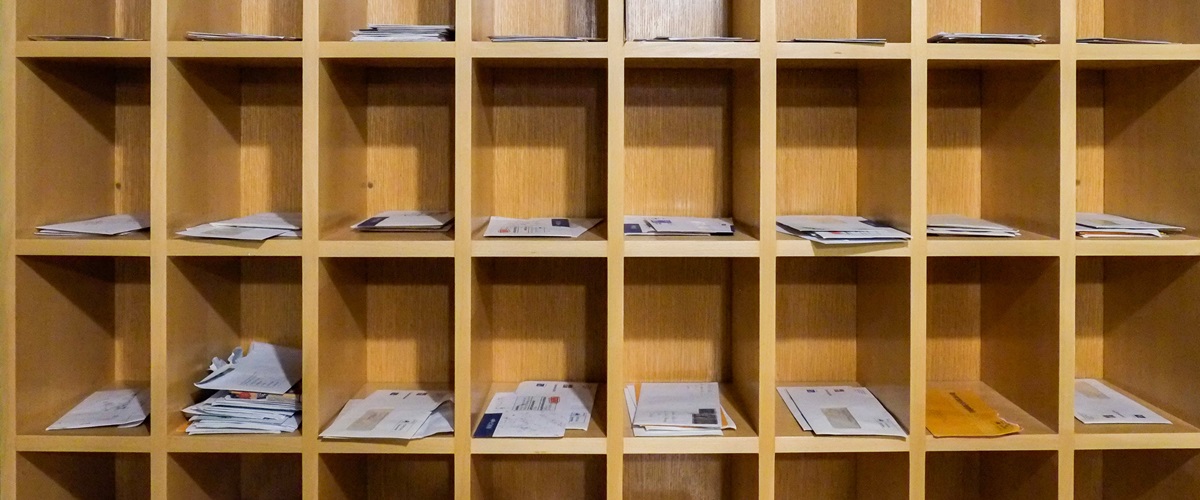Office mailroom sorter with mail in slots.