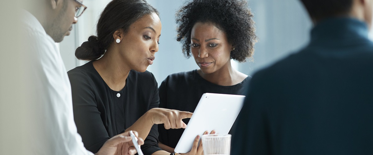 Office workers gather around a tablet to discuss the latest digitized reports.