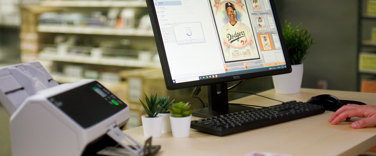 Image of a baseball sports card on a computer screen with a Ricoh scanner next to it. 