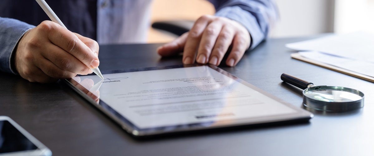 A person signs a digital document displayed on a tablet, representing one of the many types of unstructured data an organization might hold.