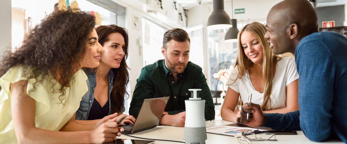 Five workers in a conference room on a video conferencing call. 