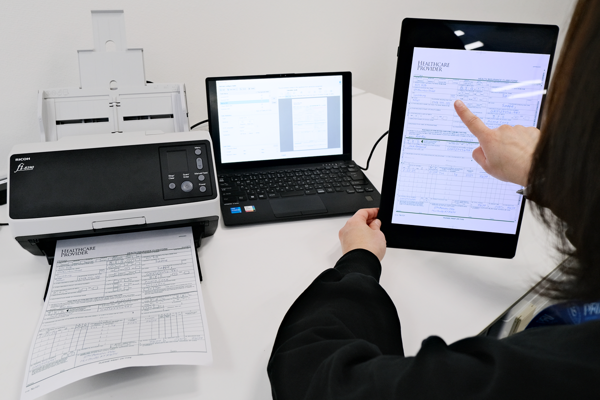Ricoh fi-8190 Document Scanner with a laptop with PaperStream Capture Pro software open and tablet on a desk.