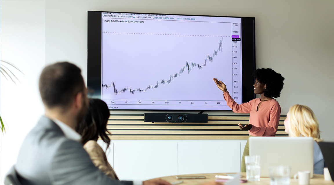 Image of people gathered around a tv screen showing a graph.